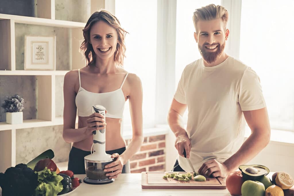 About Me 5 Ivy and Marcus preparing healthy meals together in a bright kitchen, smiling and using fresh vegetables, showing their passion for cooking and nutrition