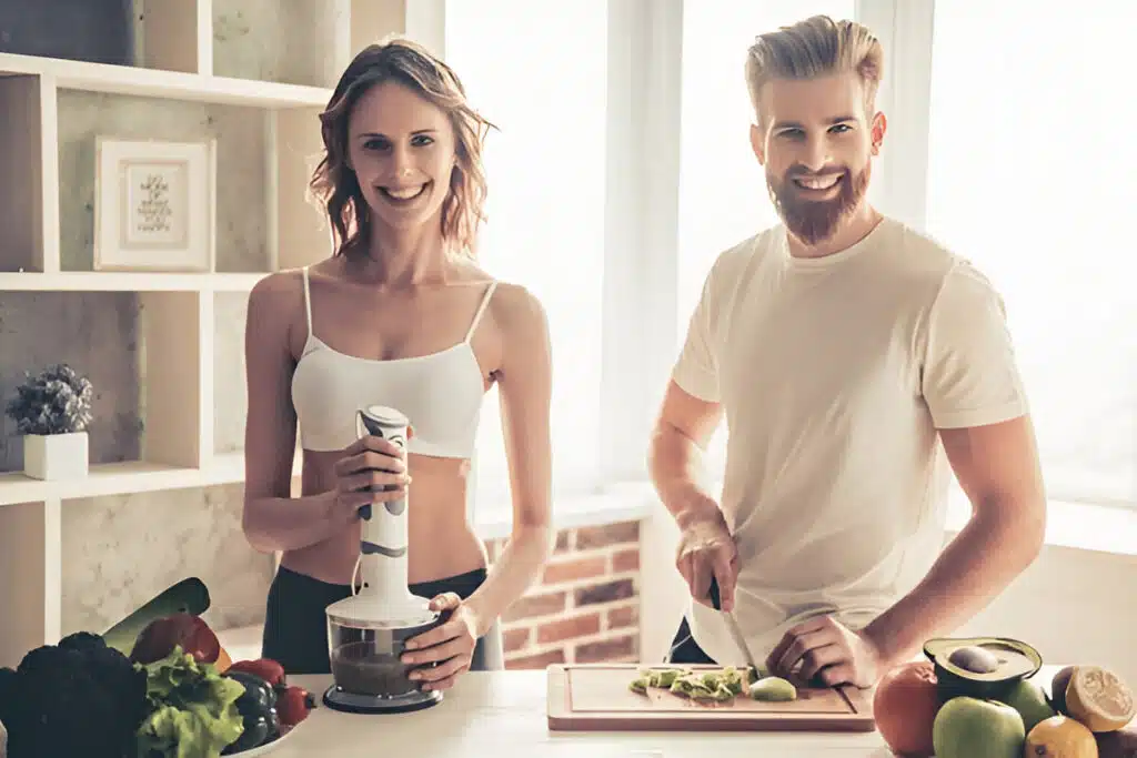 About Me 5 Ivy and Marcus preparing healthy meals together in a bright kitchen, smiling and using fresh vegetables, showing their passion for cooking and nutrition